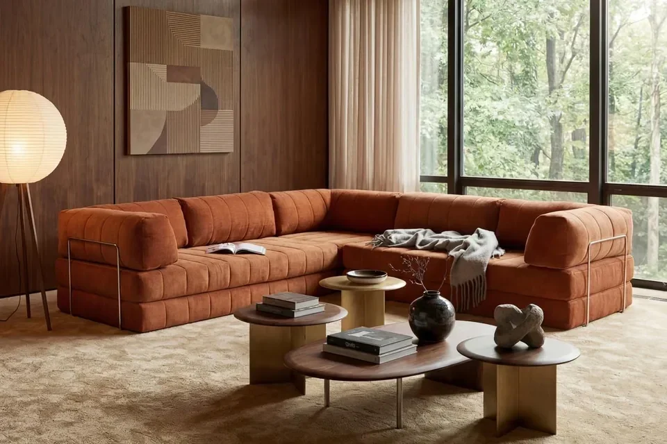 Terrakottafarbenes Innovation Living Sofa CozyPad in einem Wohnraum mit Holz und großen Fenstern