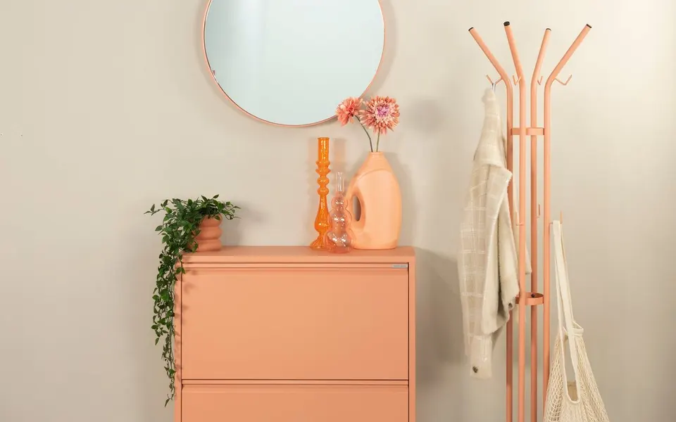 Apricotfarbener Schuhschrank mit passender Garderobe, rundem Spiegel und Grünpflanze – Spinder Design