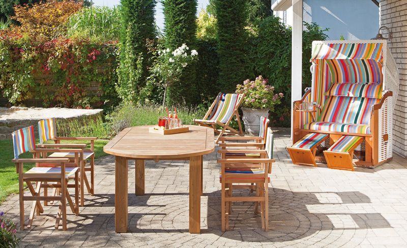 Terrasse mit einem Gartentisch, Holzstühlen und einem Strandkorb